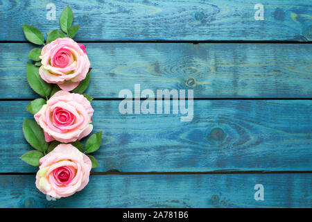 Hochzeit Grenze mit drei rosa Rose Blumen auf blau Holz- Hintergrund Stockfoto