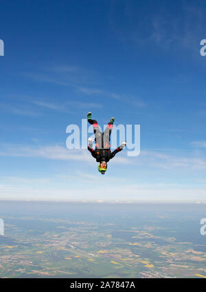 Dieser Spaß Jumper fliegen hoch in den Himmel und die Schulung der Kopf nach unten positionieren. Bald muss er seinen Fallschirm zu öffnen ein Fallschirmspringer zu speichern. Stockfoto