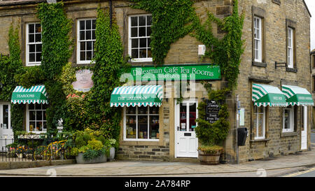 Die Außenseite des malerisch einladenden sonnigen Efeu bewachsenen Dalesman Café Teestube & Süße Emporium (Name über der Tür) - Gargrave, North Yorkshire, England, UK. Stockfoto
