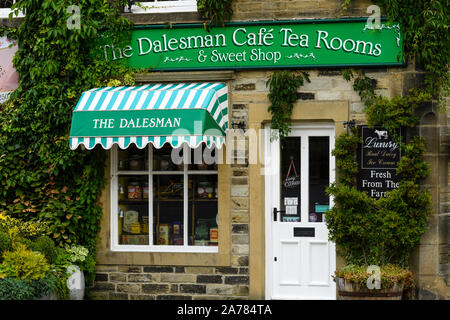 Die Außenseite des malerisch einladenden sonnigen Efeu bewachsenen Dalesman Café Teestube & Süße Emporium (Name über der Tür) - Gargrave, North Yorkshire, England, UK. Stockfoto