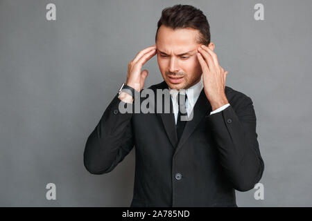 Geschäftsmann Studio stehen isoliert auf Grau in Kopfschmerzen Kopf unglücklich berühren. Stockfoto