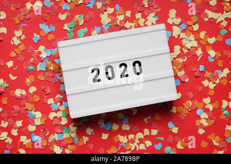 2020 lightbox Zeichen auf rotem Papier Hintergrund mit Konfetti - Silvester Party Feier Konzept flach Stockfoto