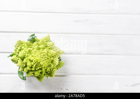 Frisches Grün Romanesco, rohe organische Kohl Bereit für das Kochen auf einem Schneidebrett auf weißem Holz- Hintergrund Stockfoto