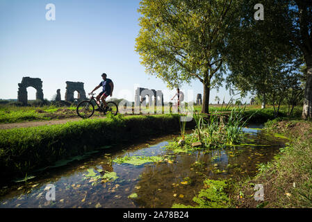 Rom. Italien. Parco degli Acquedotti, Radfahrer vorbei an der alten römischen Aquädukt Aqua Claudia, von Kaiser Caligula in 38 AD begonnen und von Kaiser abgeschlossen Stockfoto