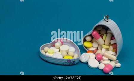 Eisen Herz box für Tabletten auf einem blauen Hintergrund. Rund, oval, weiß, rot. close-up Stockfoto