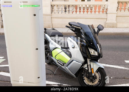 BMW C Evolution elektrische Motorroller, Motorrad, angeschlossen an ein Circutor Ladestation auf einer Straße in Santa Cruz de Tenerife, Kanarische Inseln, Spanien Stockfoto