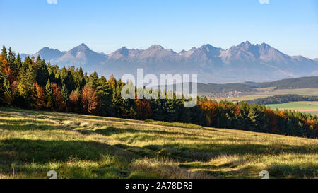 Die Gipfel der Hohen Tatra auf einem sonnigen Herbsttag mit Bäumen Ändern der Farben der Blätter Stockfoto