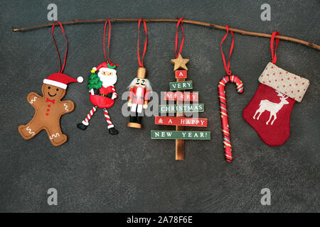 Weihnachtsschmuck hängen an einem Zweig mit Nussknacker Soldat, Baum, Zuckerstange, Bevorratung und Gingerbread Man auf Grau grunge Hintergrund. Stockfoto