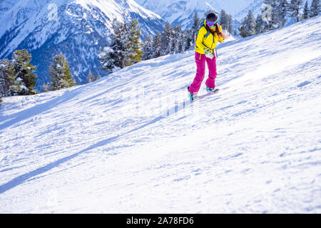 Foto der jungen Sportlerin im Helm Snowboarden im Winter Resort am Nachmittag Stockfoto