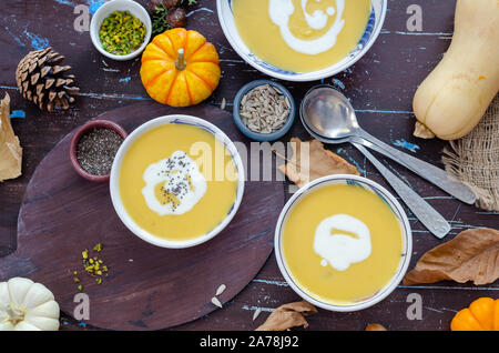 Kürbiscremesuppe mit Kürbiskernen auf braunen Tisch. Stockfoto