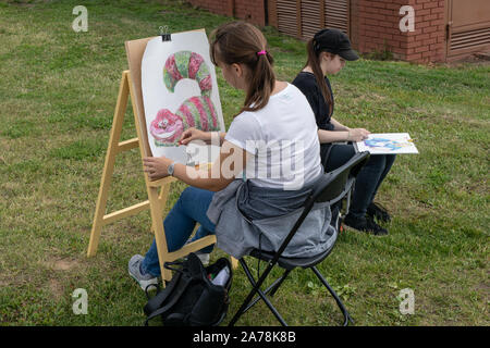 Schüler zeichnen auf Staffeleien in einem Park auf einer Wiese. KAZAN, Russland - Juli 08, 2016 Stockfoto