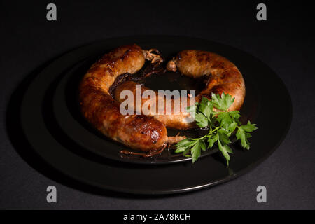 Köstliche frische hausgemachte Wurst auf einer schwarzen Platte Stockfoto