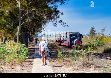 Landschaftlich schöner Personennahverkehr mit der Miniatureisenbahn, der Passagiere zum Strand von Barril, Santa Luzia, Ostalgarve, Portugal bringt. Stockfoto