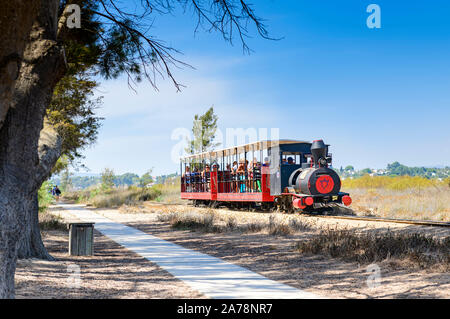 Landschaftlich schöner Personennahverkehr mit der Miniatureisenbahn, der Passagiere zum Strand von Barril, Santa Luzia, Ostalgarve, Portugal bringt. Stockfoto