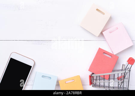 Abstract online shopping, mobile Payment Konzept Design Element, bunt Warenkorb und Papiertüten auf weißem Hintergrund Holz- Tabelle, Ansicht von oben, flach Stockfoto
