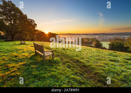 Holzbank über misty High Weald Landschaft bei Sonnenaufgang, Burwash, East Sussex, England, Vereinigtes Königreich, Europa Stockfoto