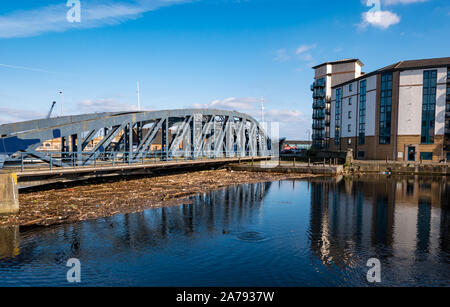 Leith, Edinburgh, Schottland, Großbritannien, 31. Oktober 2019. UK Wetter: Sonnenschein spiegelt Gebäude im Wasser von Leith. Strandgut Rückstände aufgrund der hohen Niederschläge in diesem Jahr füllt das Becken durch die alten Victoria Swing Bridge, die eine unansehnliche Chaos für Anwohner Stockfoto