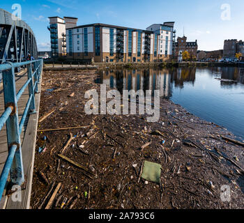 Leith, Edinburgh, Schottland, Großbritannien, 31. Oktober 2019. UK Wetter: Sonnenschein spiegelt Gebäude im Wasser von Leith. Strandgut Rückstände aufgrund der hohen Niederschläge in diesem Jahr füllt das Becken durch die alten Victoria Swing Bridge, die eine unansehnliche Chaos für Anwohner Stockfoto