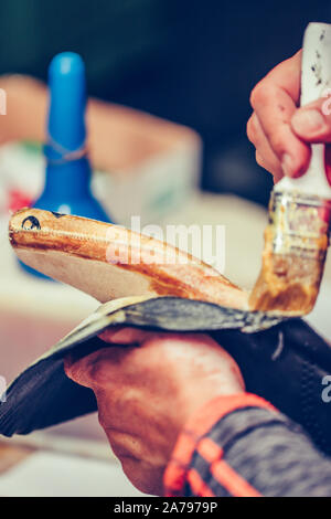 Die Hände eines erfahrenen Arbeiter in den handgefertigten Schuhindustrie, alleinige kleben Aufgaben, Leim auf die Teile der Schuh. Stockfoto