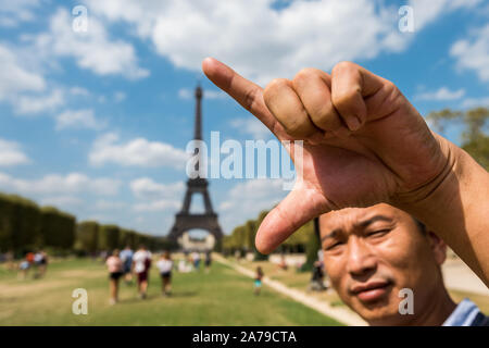 Ein chinee Mann mit seiner Hand die Länge Eiffelturm, einem schmiedeeisernen zu messen - Eisen Gitterturm auf dem Champ de Mars in Paris, Frankreich, benannt nach der en Stockfoto