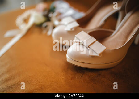 Hochzeit Zubehör Braut. Stilvolle beige Schuhe, Knopfloch und Strumpfband auf Holz- Hintergrund. Stockfoto