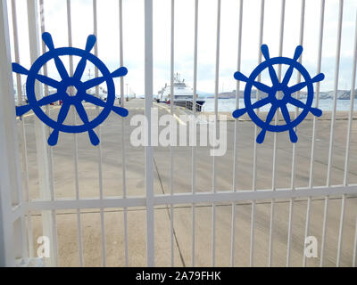 Blick auf den Hafen durch die Weißen Toren mit zwei blauen Ruder im Hintergrund ein Schiff im Hafen angedockt Stockfoto