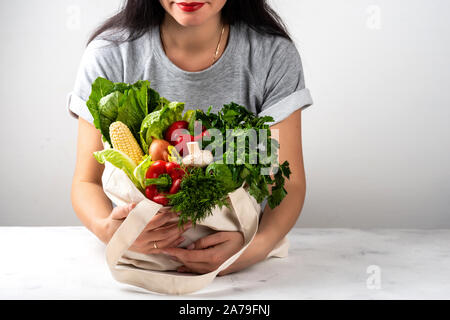 Frau hält einen Stoff eco Beutel voll von verschiedenen frisches Gemüse in der hellen Küche. Käufe Konzept null Abfall. Saubere Diät essen. Stockfoto