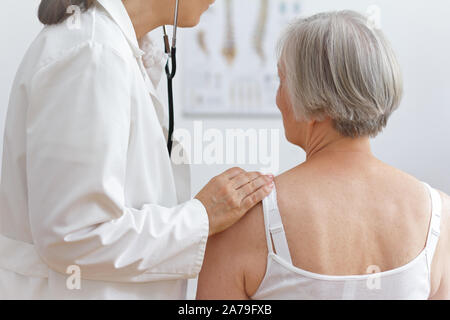 Health Care Konzept: Ärztin auscultating im Herzen von ein älterer Patient mit einem Stethoskop. Stockfoto