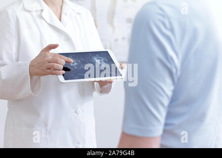 Rückenschmerzen Konzept: Arzt mit Tablet-PC zeigen Ihr Patient Katze Bilder ihrer Lendenwirbelsäule scannen. Stockfoto