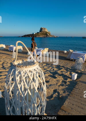 Touristische Spaziergänge am Strand vor der Laterne während der Vorbereitung Abendessen vor der Insel Kastri bei Sonnenuntergang Stockfoto