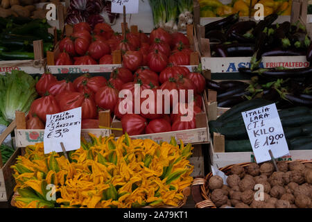 Ungewöhnlich helle rote Tomaten und andere Gemüse in Kisten zum Verkauf auf einen Markt angezeigt Stall in Venedig. Stockfoto