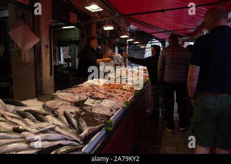 Fischhändler Verkauf von einer fantastischen langen Sitzbank von Fischen unter einem roten Baldachin der traditionellen Fischmarkt in Venedig. Stockfoto