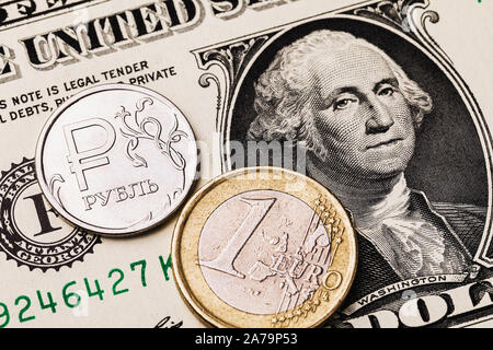 Ein Euro Münze und Russische Rubel vor dem Hintergrund von einem Dollar Bill. Die Münze hat eine Inschrift in russischen Buchstaben Rubel Stockfoto