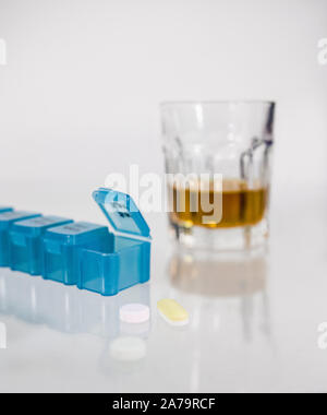 Ein Glas Alkohol neben einer Medikation pod und Pillen. Kopieren Sie Raum, High Key. Stockfoto