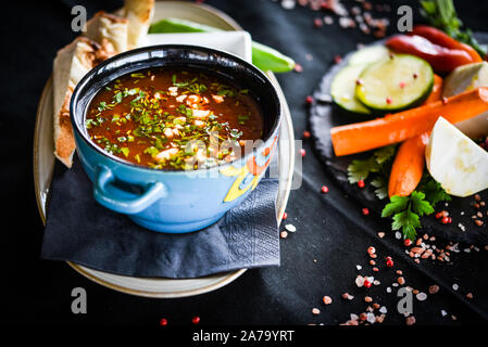 Traditionelle türkische Suppe aus Rumänien mit frischem Gemüse, Wischcreme, Gewürzen und hausgemachtem Brot Stockfoto
