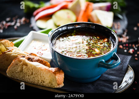 Traditionelle türkische Suppe aus Rumänien mit frischem Gemüse, Wischcreme, Gewürzen und hausgemachtem Brot Stockfoto