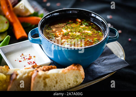 Traditionelle türkische Suppe aus Rumänien mit frischem Gemüse, Wischcreme, Gewürzen und hausgemachtem Brot Stockfoto