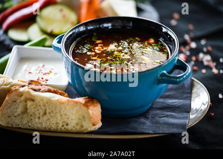 Traditionelle türkische Suppe aus Rumänien mit frischem Gemüse, Wischcreme, Gewürzen und hausgemachtem Brot Stockfoto