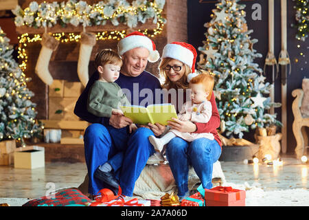 Großeltern lesen Sie ein Buch für Kinder in Weihnachten Stockfoto