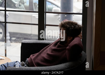 Hübscher junger Geschäftsmann ruht im Cafe. Attraktive bärtiger Mann am Tisch ist in der Cafeteria sitzen und Träumen. Stockfoto