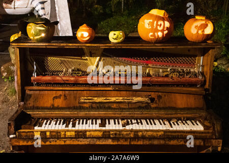 Spooky Halloween Kürbisse, Jack O Lantern, mit brennenden Kerzen an einem alten Grand Piano Stockfoto