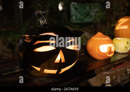 Spooky Halloween Kürbisse, Jack O Lantern, alte Hexe mit Hut, mit brennenden Kerzen Stockfoto