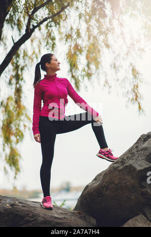 Schöne Sportlerin stretching auf dem Felsen im Herbst Park. Stockfoto