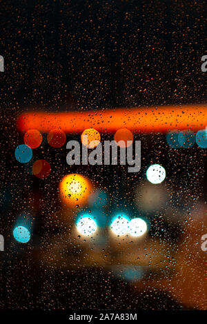 Wasser Tropfen am Fenster und Bokeh der Stadt in den Sonnenuntergang. Stockfoto