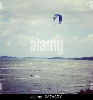 Ein einsamer Mann ist durch die Aktion Sport Kitesurfen an einem windigen Tag im südlichen Schweden Stockfoto