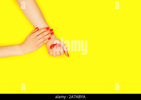 Stilvoll trendy, Buchse, rot, Maniküre. Zwei schöne Frau Hände mit Maniküre auf gelben Hintergrund. Für Text platzieren. Stockfoto
