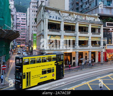 Straßenbahn vorbei an alten kolonialen Gebäude jetzt Restaurants und Bar namens der Bauer in Wanchai, Hongkong Stockfoto