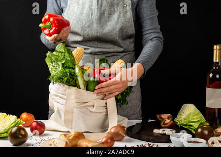 Frau hält eine Baumwolle eco Beutel voll von verschiedenen frischen Gemüse und rote Paprika in der Hand. Kochen gesund sauber. das Essen. Null Abfall Käufe Konzept. Stockfoto