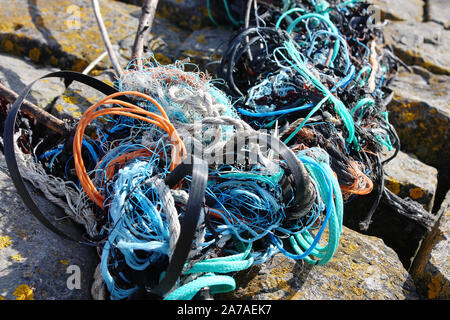 Hintergrund der gewaschen an Land tangled Orange, Blau, Grün und Weiß Kunststoff Leitungen und Seilen. Konzept der Kunststoffabfälle. Stockfoto