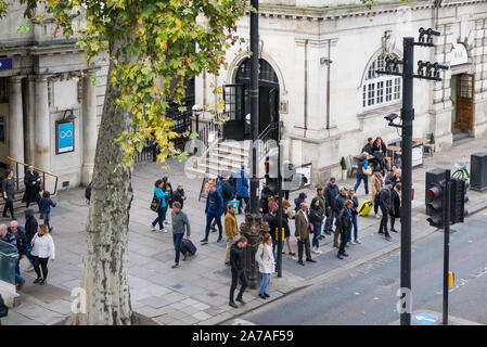 Die Menschen warten auf einem Zebrastreifen die Straße am Victoria Embankment außerhalb der U-Bahnstation Embankment, London, England, UK zu überqueren Stockfoto